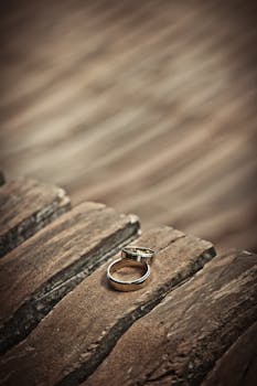 Close-up of elegant silver wedding rings on a rustic wooden surface, symbolizing love and unity.