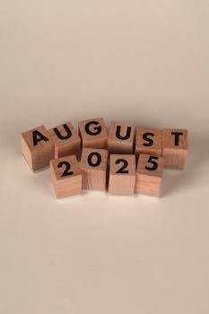 Wooden blocks arranged to spell the date August 2025 on a neutral background.